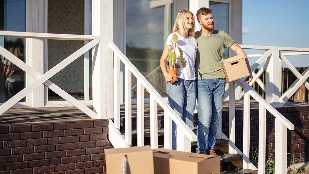 Couple Standing on steps on new house with moving boxes after their home inspection